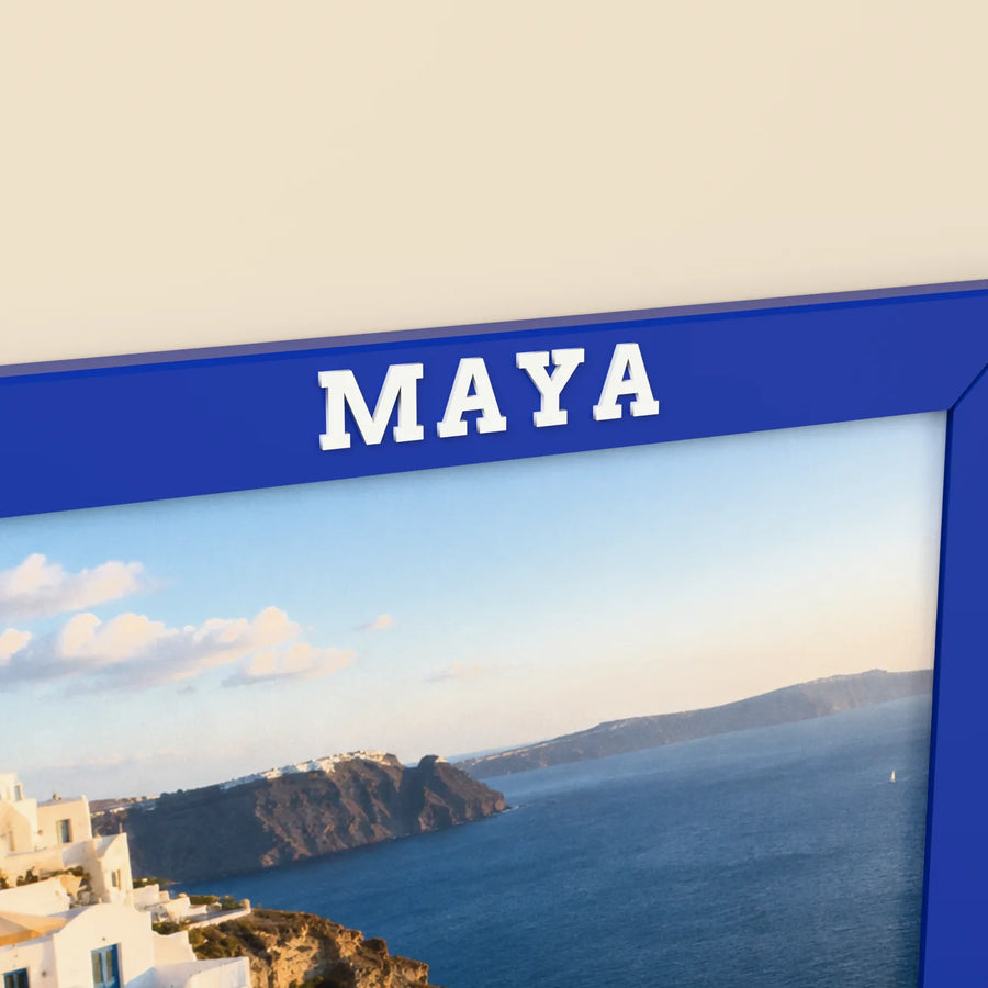 Close-up of the name MAYA in raised white letters on the top of a blue framylo frame